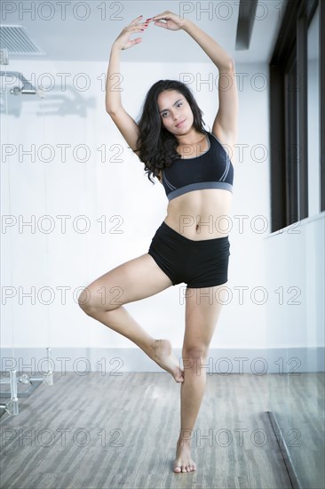 Hispanic woman practicing yoga in studio