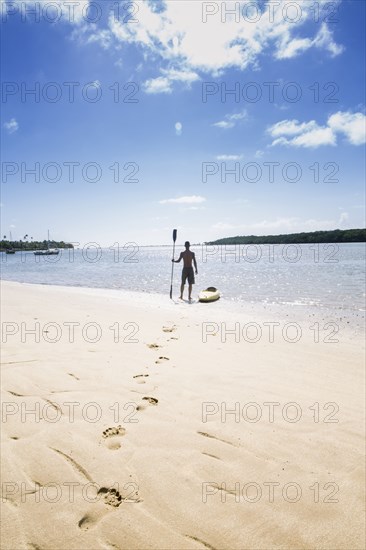 Native American man with kayak on beach