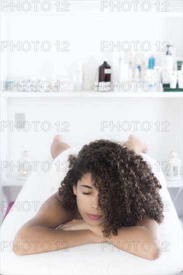 Hispanic woman laying on massage table in spa