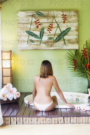 Hispanic woman sitting at hot tub in spa