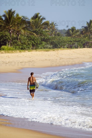 Mixed race surfer carrying surfboard on beach