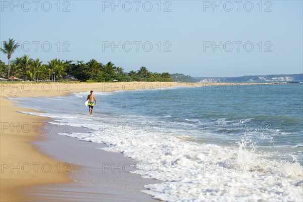 Mixed race surfer carrying surfboard on beach