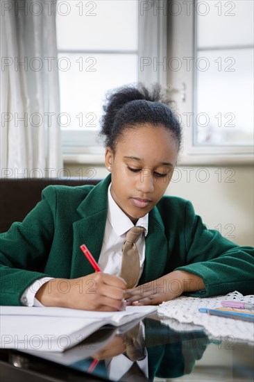 Black girl wearing school uniform doing homework