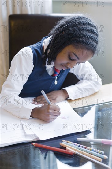 Black girl wearing school uniform doing homework