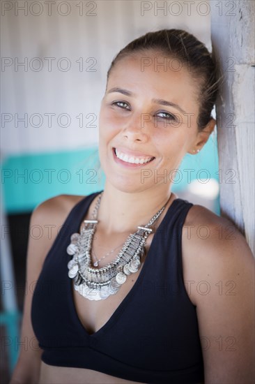 Smiling hispanic woman wearing necklace and bikini