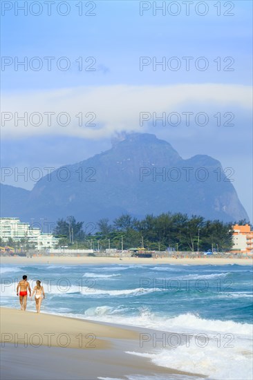 Couple walking on beach near waves