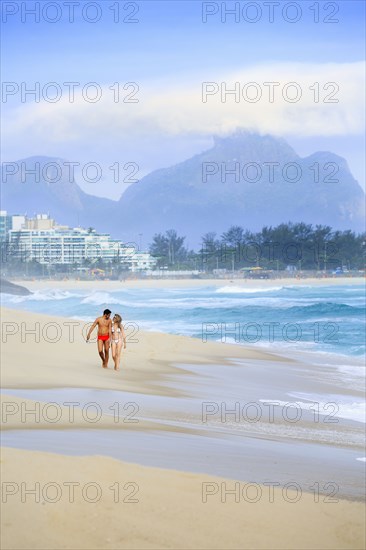 Couple walking on beach near waves