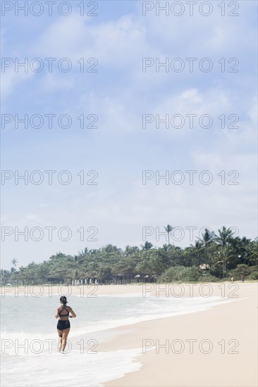 Mixed Race girl running on beach in waves