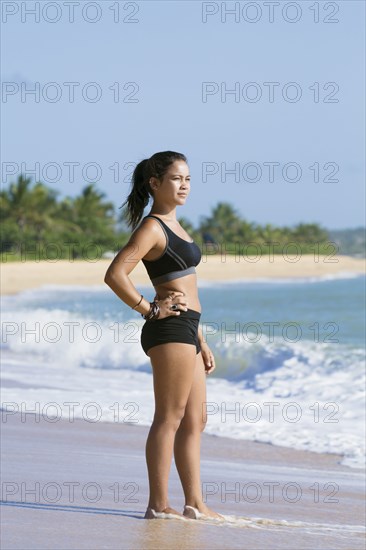 Pensive Mixed Race girl standing on beach