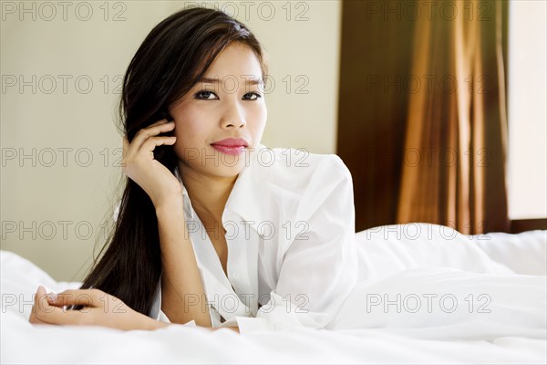 Portrait of serious Asian teenage girl laying on bed