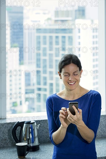 Caucasian woman texting on cell phone near window