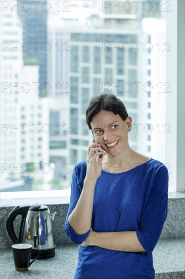 Caucasian woman talking on cell phone near window