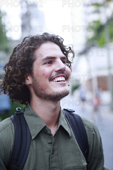 Smiling man carrying backpack in city