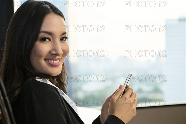 smiling Asian businesswoman texting on cell phone