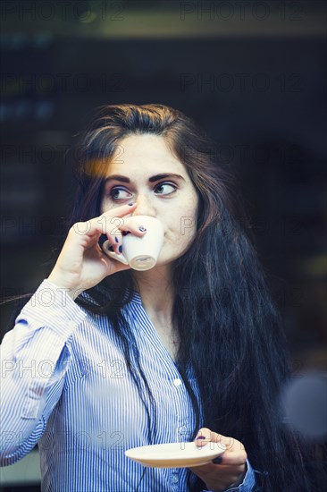 Curious Caucasian woman sipping coffee outdoors