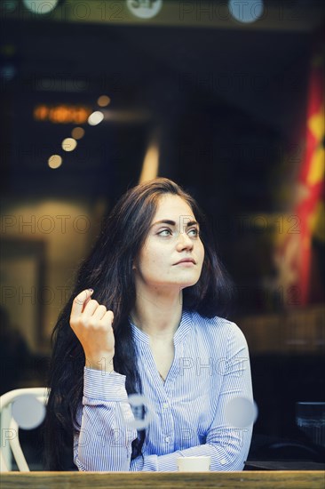 Pensive Caucasian woman drinking coffee at cafe