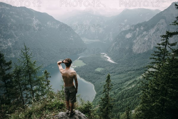 Caucasian man standing on rock overlooking lake in valley