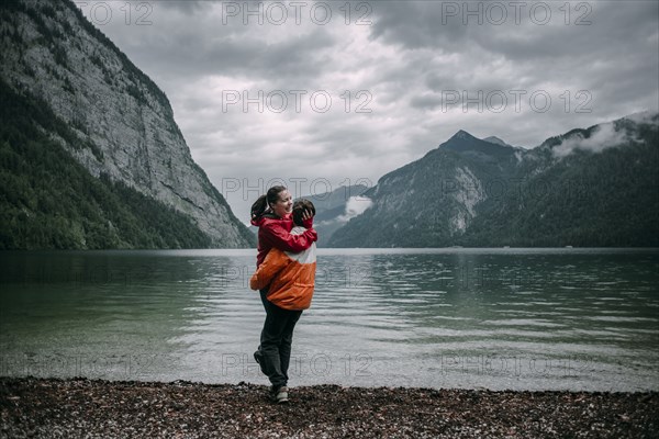 Caucasian man hugging near mountain lake