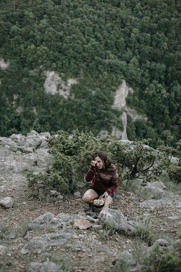 Smiling Caucasian woman crouching on mountain holding pan