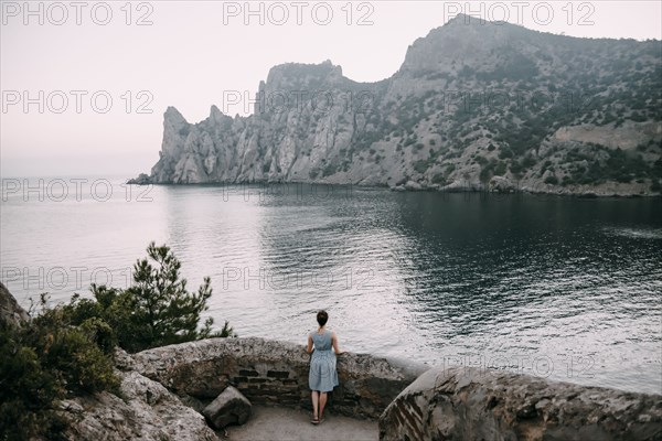 Caucasian woman standing at stone wall admiring ocean