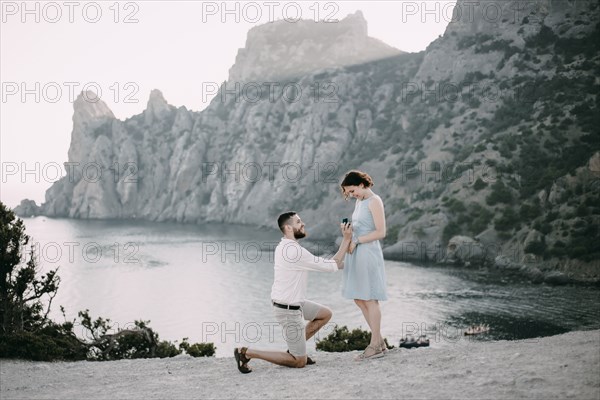 Caucasian man proposing marriage to woman at beach