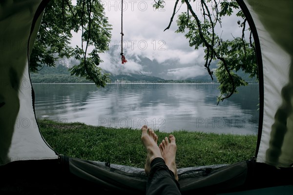 Feet on man laying in camping tent at lake