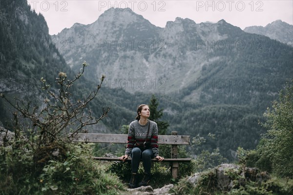 Caucasian woman sitting on bench in mountains