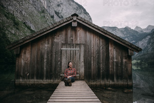 Caucasian woman sitting on dock at remote cabin