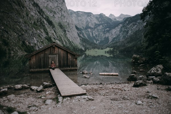 Caucasian woman sitting on dock at remote cabin