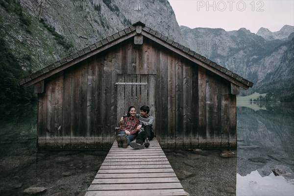 Caucasian couple sitting on dock at remote cabin