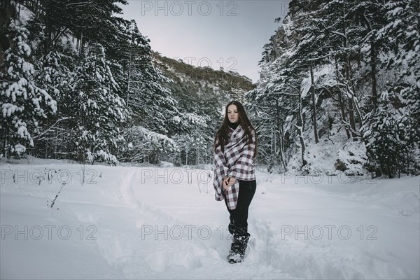 Caucasian woman wrapped in blanket in snowy forest