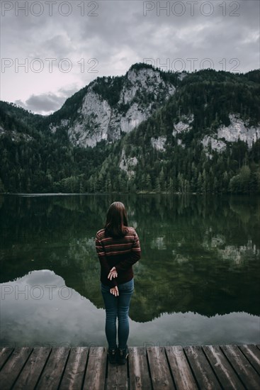 Caucasian woman standing on dock admiring scenic view of mountain