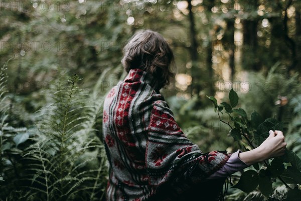 Caucasian woman holding green leaf in forest