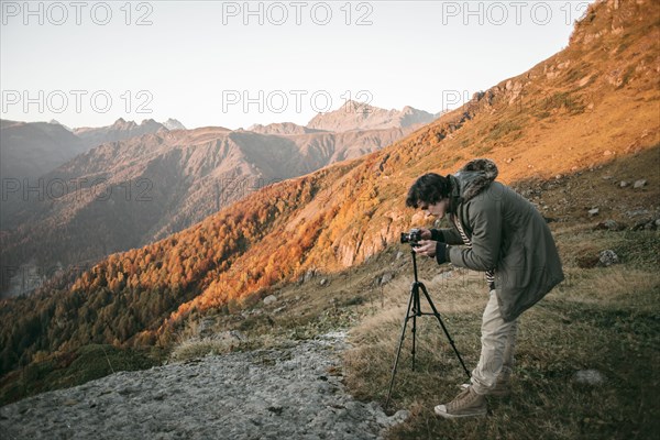 Caucasian man photographing valley from mountain