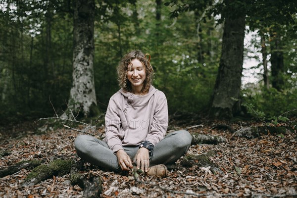 Caucasian woman sitting in autumn leaves in forest