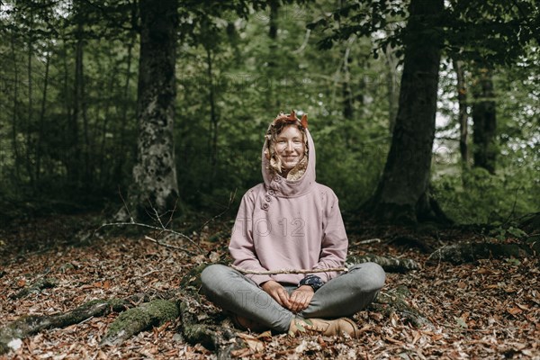 Caucasian woman sitting in with autumn leaves in hood