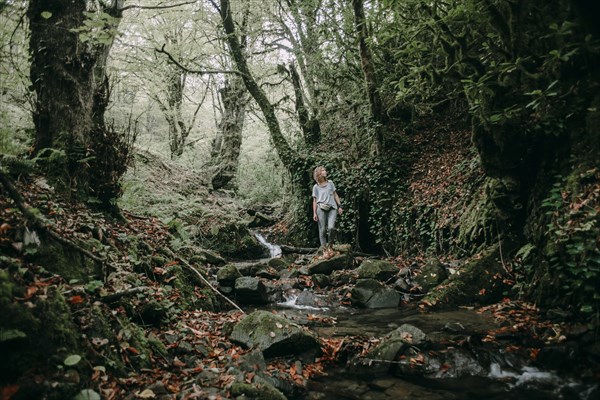 Caucasian woman standing on rock near forest stream