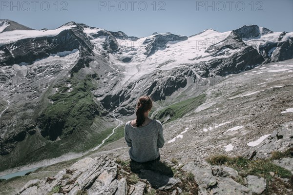 Caucasian woman sitting on rock admiring scenic view of mountain