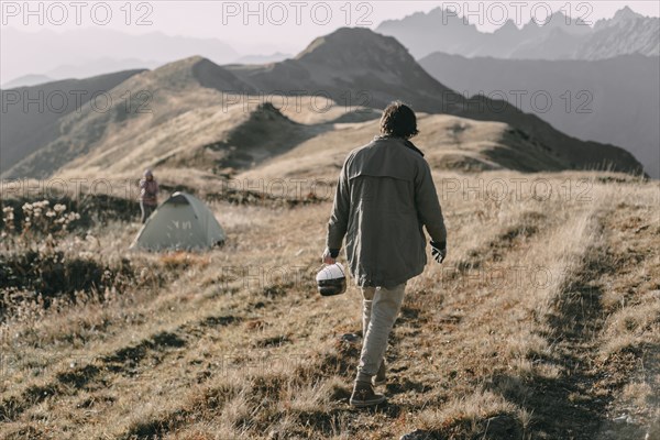 Caucasian man carrying bucket of snow to tent on mountain