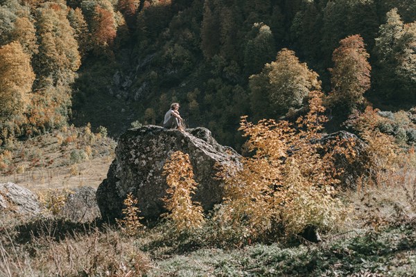 Caucasian woman sitting on boulder in autumn