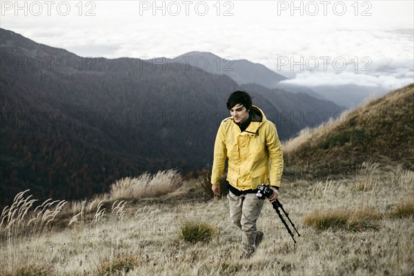Caucasian man carrying tripod in remote mountain landscape