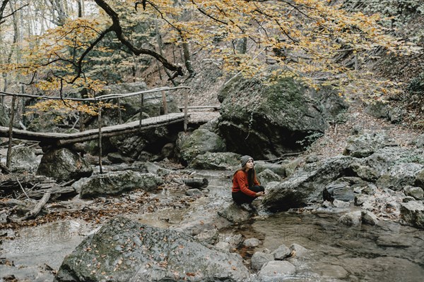 Caucasian woman sitting on rock in stream