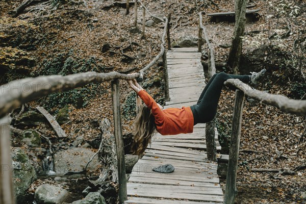 Caucasian woman playing on footbridge in woods