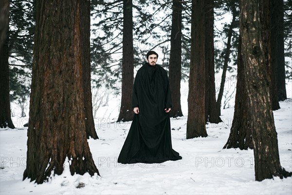 Caucasian man with beard wearing robe in forest during winter