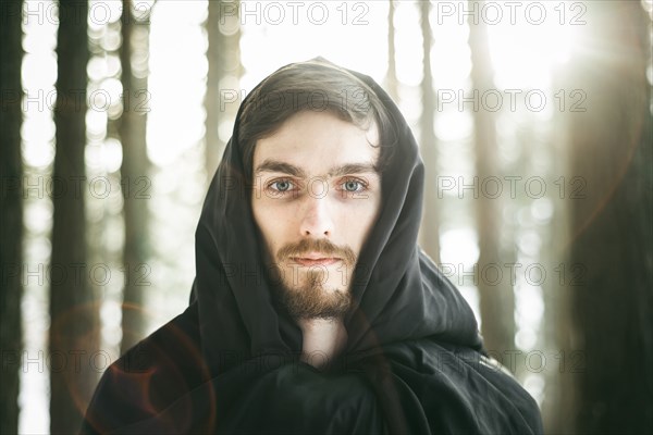 Caucasian man with beard wearing robe in forest