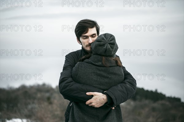 Caucasian couple hugging on hill