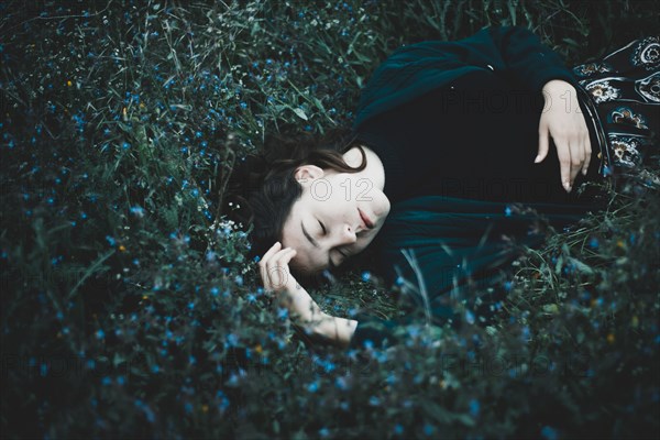 Caucasian woman laying in field of wildflowers