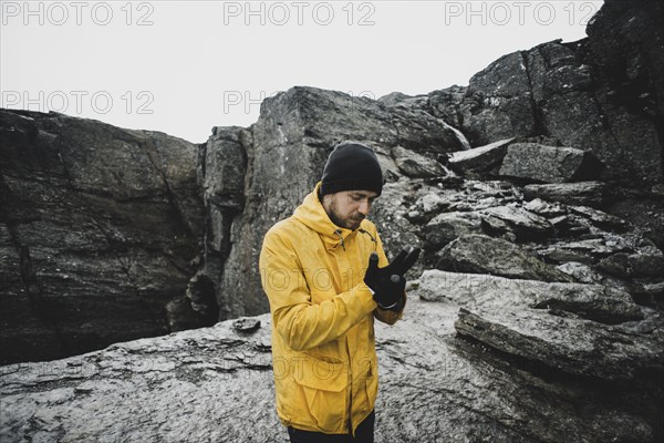 Caucasian man adjusting gloves on mountain