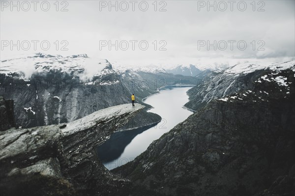 Caucasian man on cliff admiring scenic view of mountain river