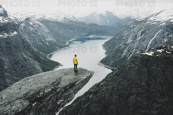 Caucasian man on cliff admiring scenic view of mountain river